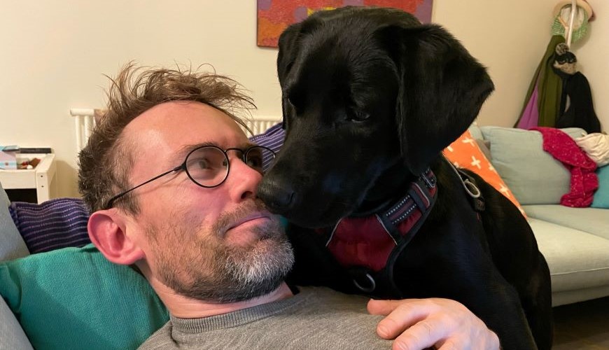 Image of Sam Drummond with a black puppy 