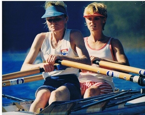 Image of Jane competing in a race. She is wearing a singlet and is rowing