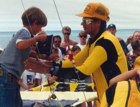 Image of Simon wearing a yellow wetsuit lifting a child into a boat 