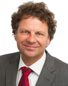 Headshot of Simon smiling at the camera. Simon is wearing a red tie and grey suit. 