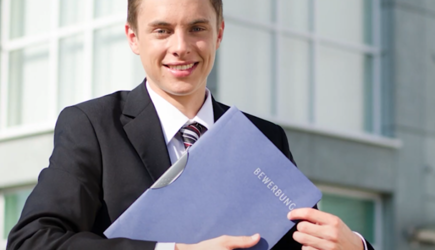 Image of a young man wearing a suit and holding a portfolio or resume. The image depicts a person going for an interview.